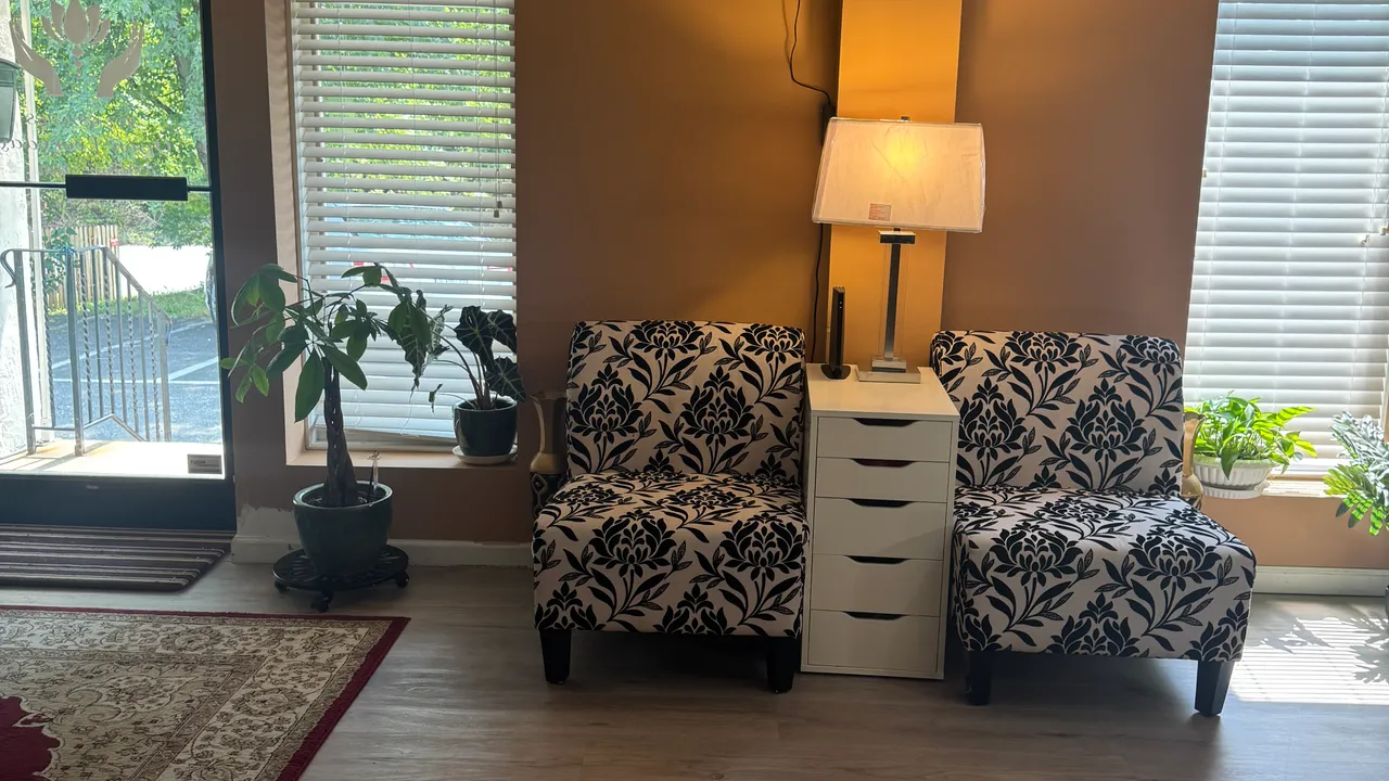 Two patterned chairs beside a lamp and windows in the waiting area at Jin’s Massage in Glenside